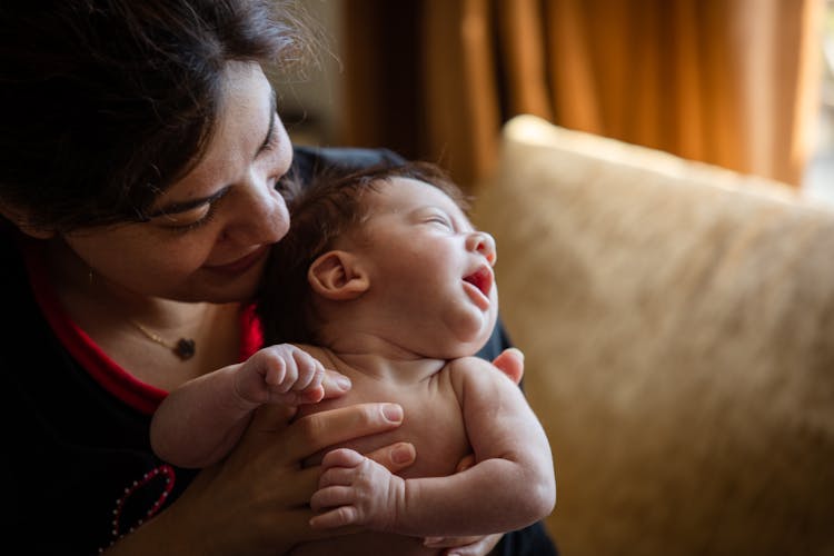 Mother Holding Her Naked Baby In Arms And Smiling