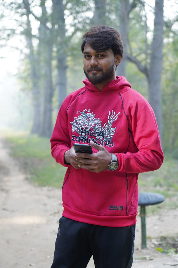 Man Wearing Red Sweatshirt With A Dragon Standing In A Park