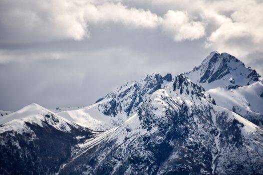 A breathtaking view of snow-covered mountain peaks under a dramatic cloudy sky, showcasing nature's grandeur.
