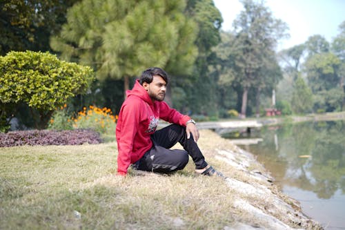 Man in Red Hoodie Sitting on the Ground
