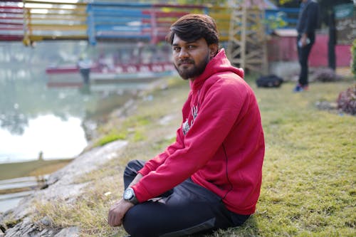 Man in Red Hoodie Sitting on the Grass