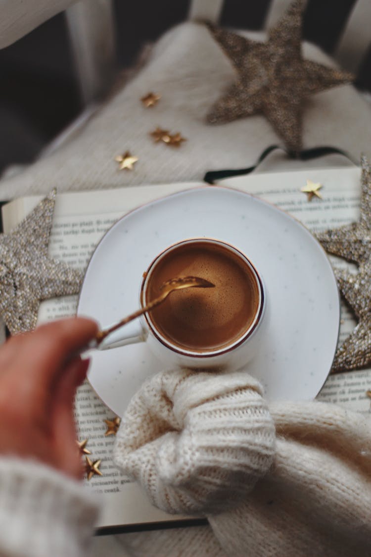 Hands Stirring Coffee With Gold Spoon