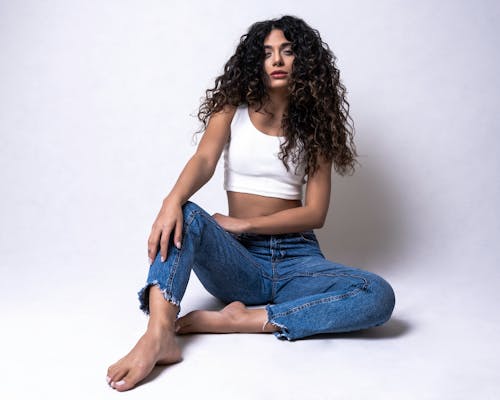 A Woman in White Tank Top and Denim Jeans Sitting on the Floor