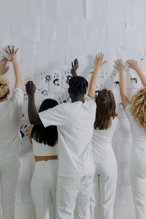 A Group of People Marking their Hands on a Wall with White Papers