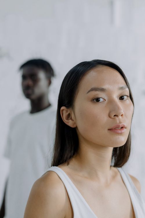 Free Close-up portrait of an East Asian woman with an African man in soft focus background. Stock Photo