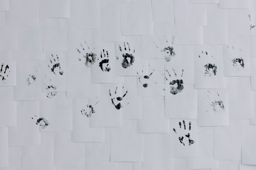 Black handprints artistically arranged on a white wall of papers, minimalist and creative still life.