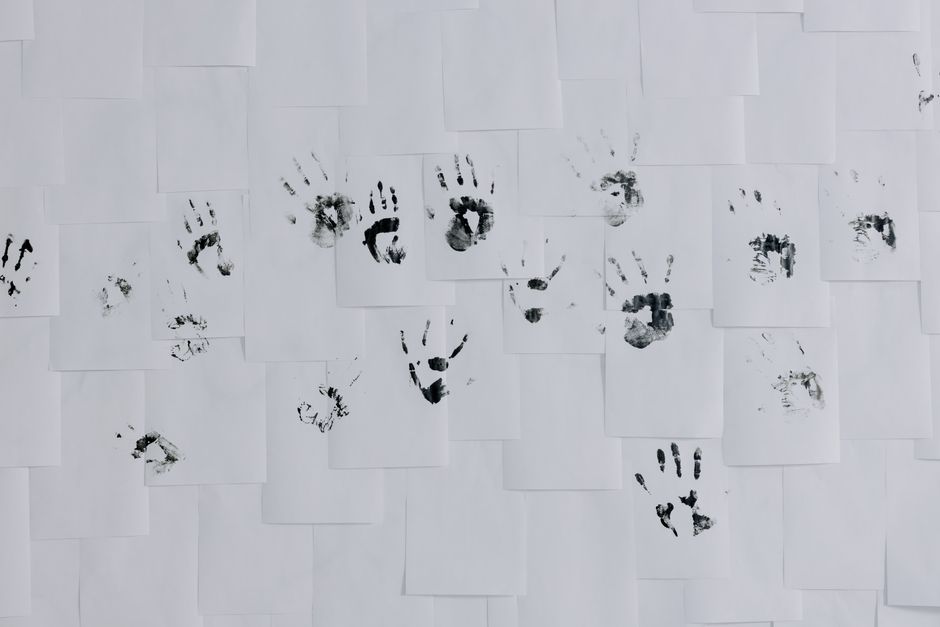 paw print decor - Black handprints artistically arranged on a white wall of papers, minimalist and creative still life.