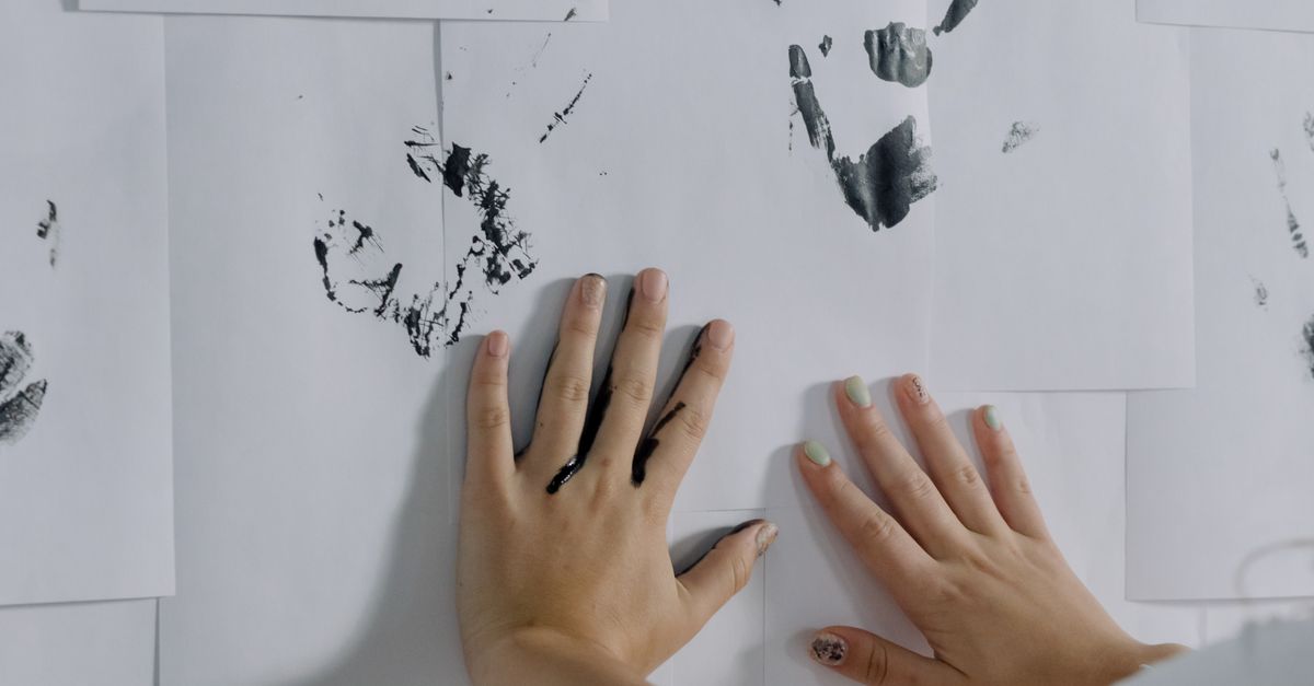 Prints Using Hand Person Hands Making Prints on Papers on Wall · Free Stock Photo
