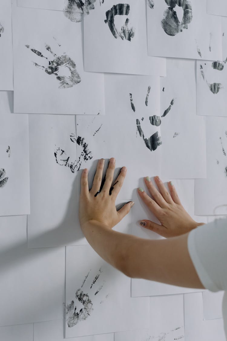 Person Hands Making Prints On Papers On Wall