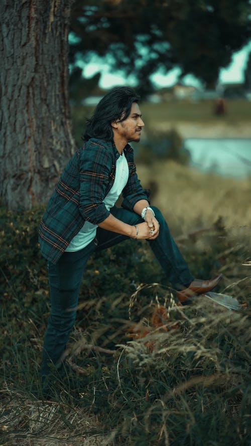 Man in a Plaid Shirt Standing Beside the Tree