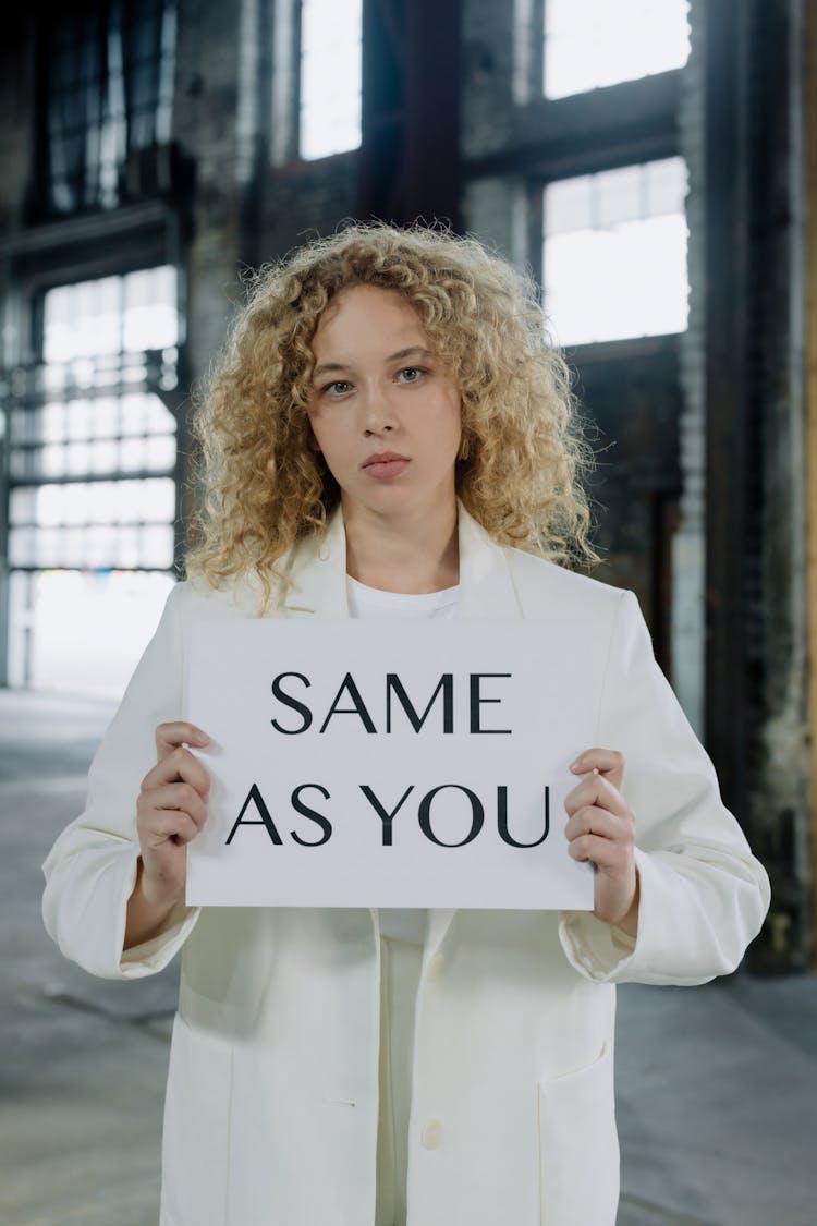 A Woman In A White Outfit Holding A Placard