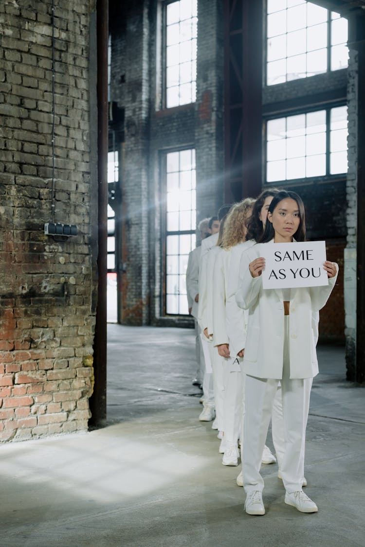 Woman In All White Outfit Holding A Paper With Message 