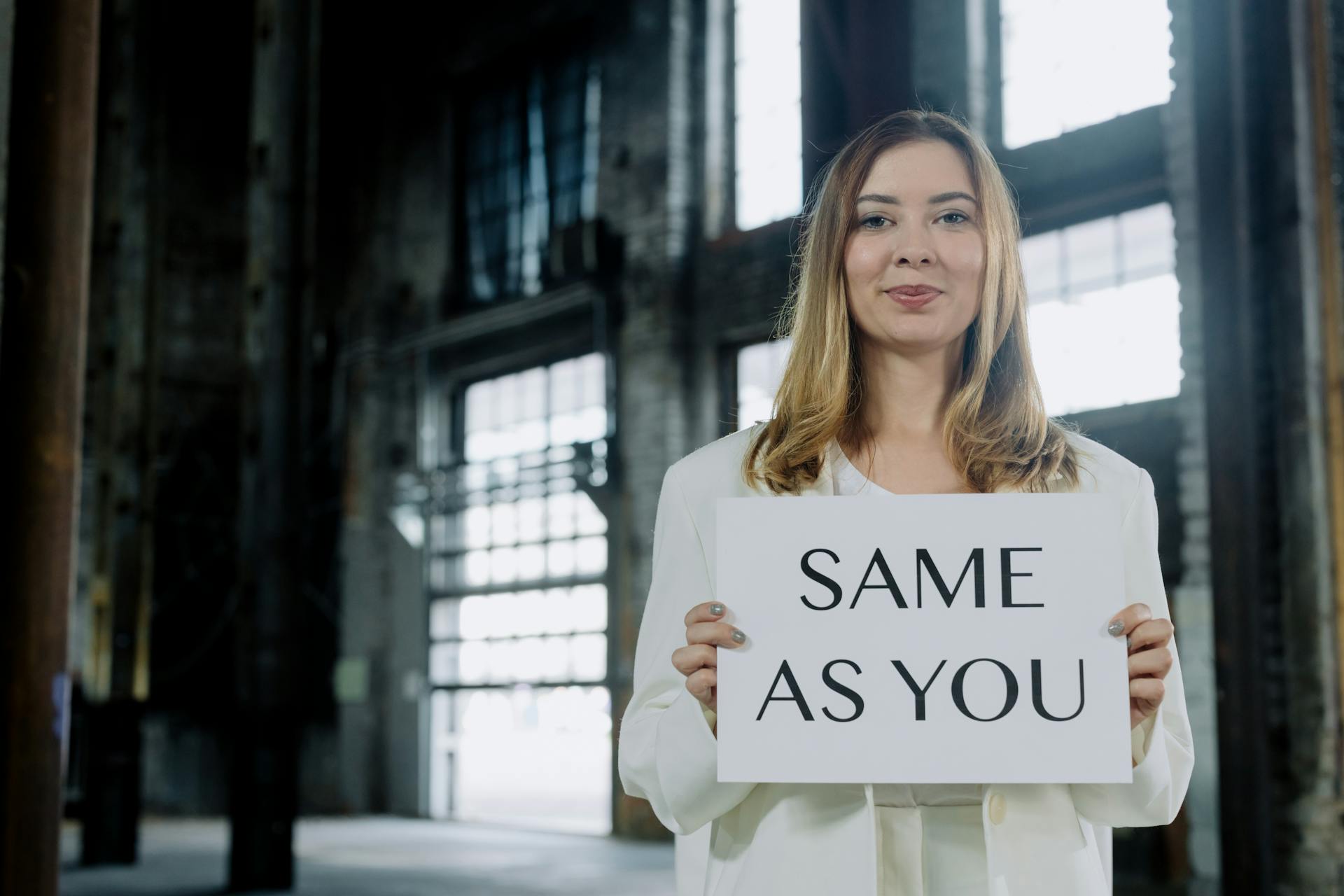 A Woman in White Blazer Holding White Paperboard with a Text Same As You