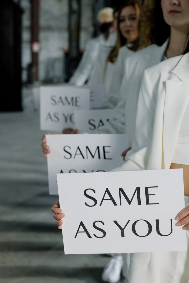 People In White Outfits Holding Placards