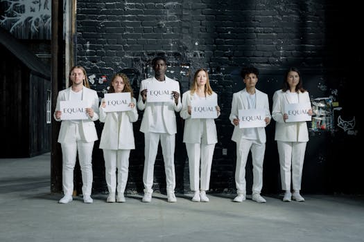A diverse group of individuals in white clothing holding 'Equal' signs against a brick wall.