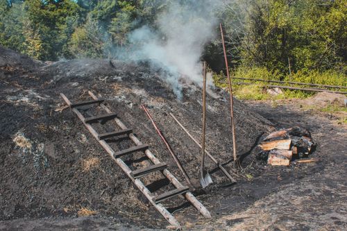 Free Smoke rises from a traditional charcoal making site in a rural setting. Stock Photo