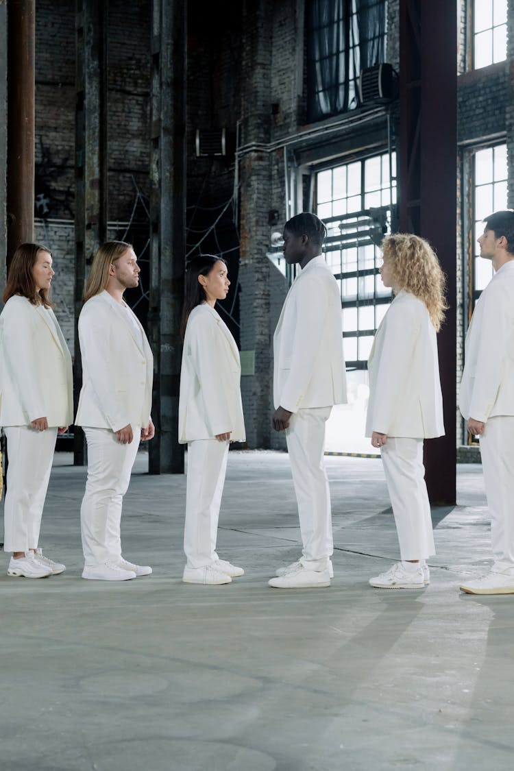 A Group Of People Wearing White Uniform In A Line Facing Each Other