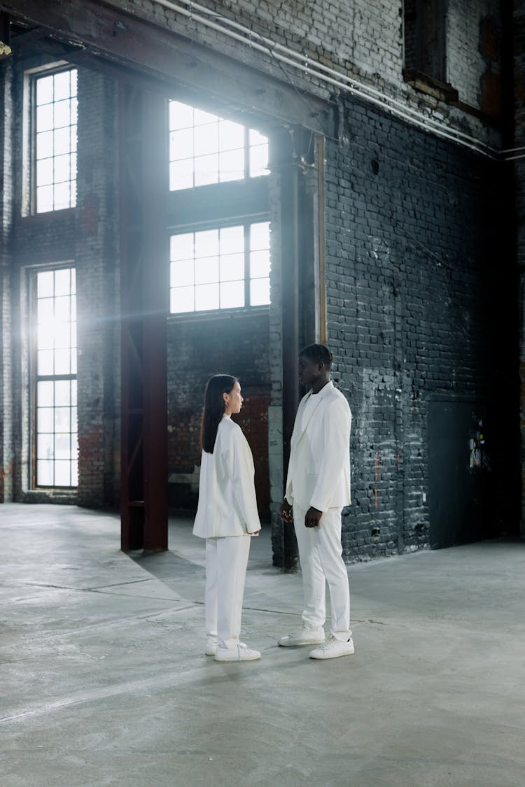 A Man And Woman In White Clothes Standing While Facing Each Other