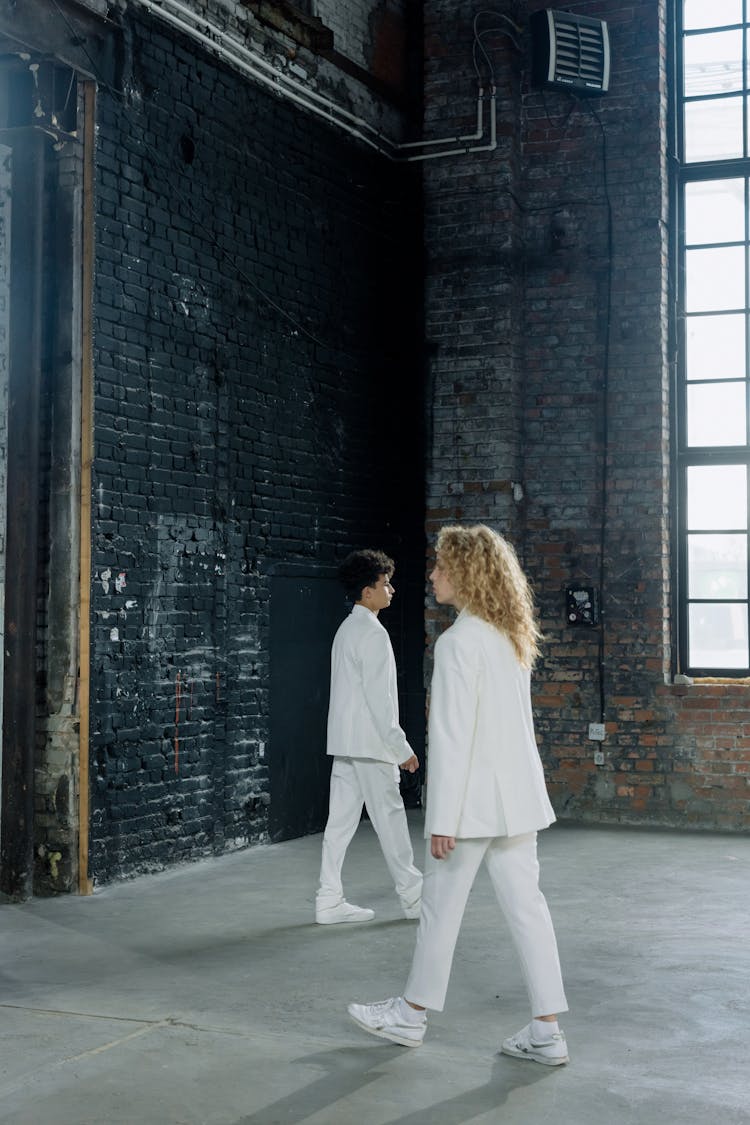 A Man And A Woman In A White Outfit Walking Indoors