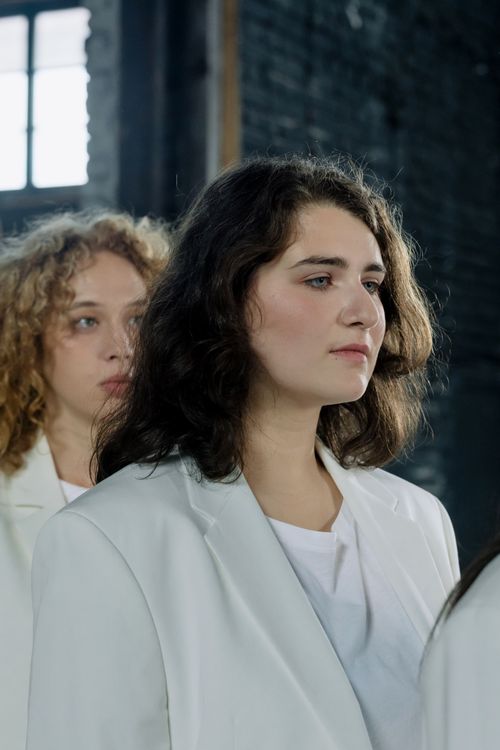 Free Two women in white blazers standing indoors with a confident pose. Stock Photo