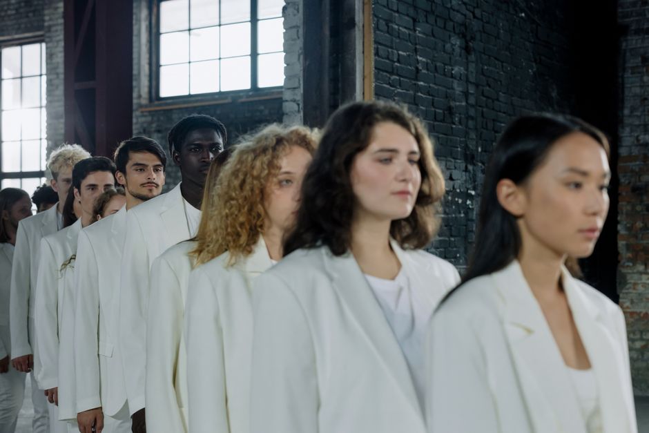 Group of diverse individuals standing in line, wearing white