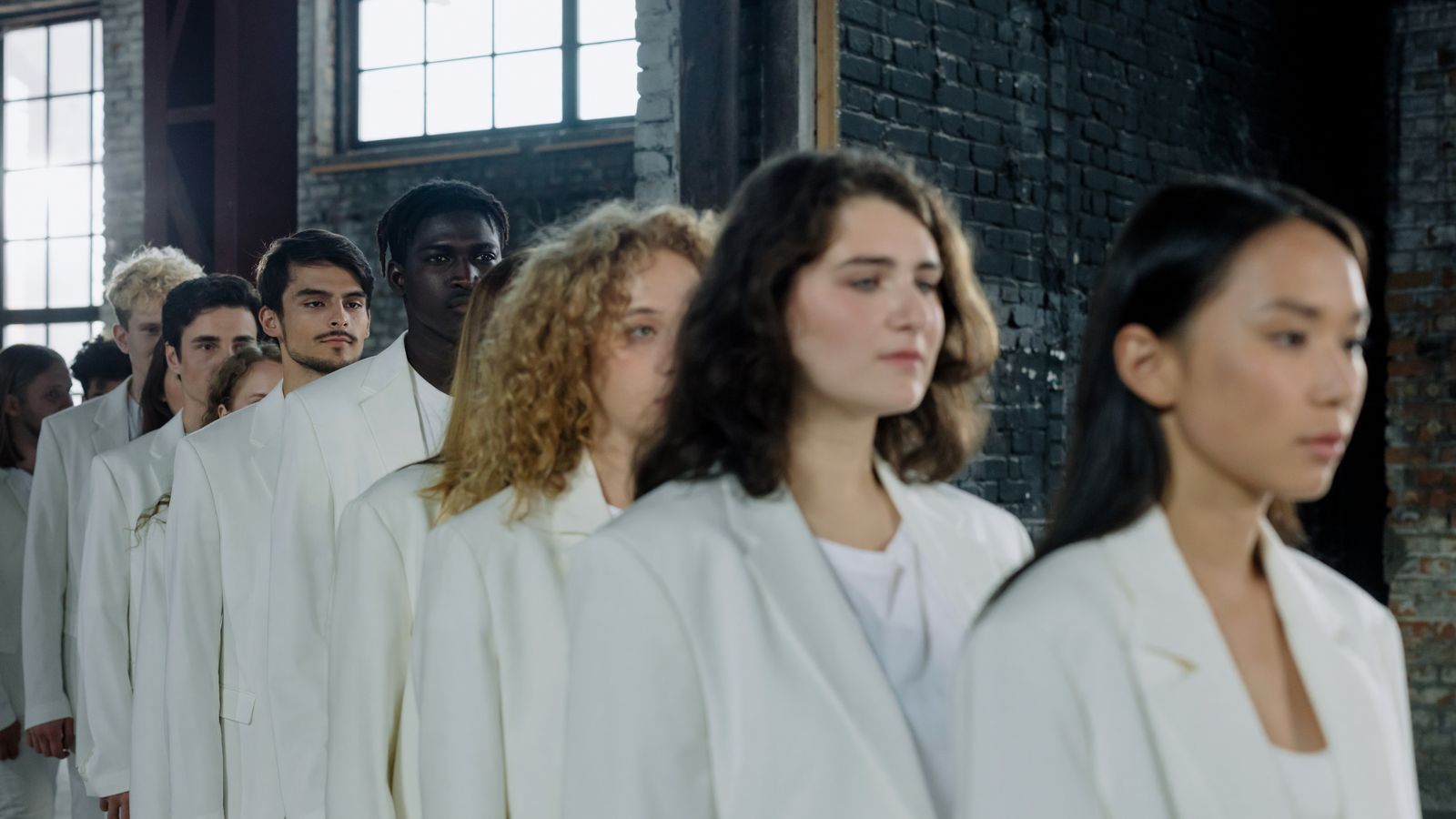 Models in coordinated white outfits walking in a line at a brand fashion show