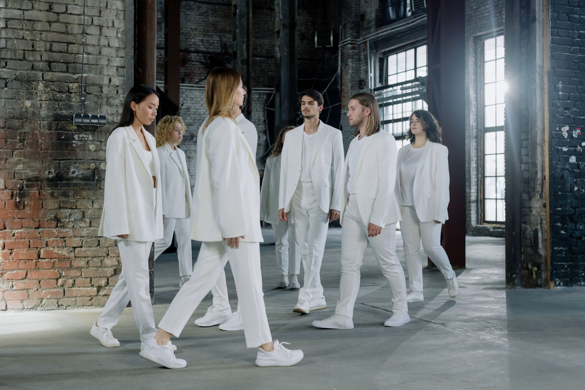 People in White Outfits Walking Indoors