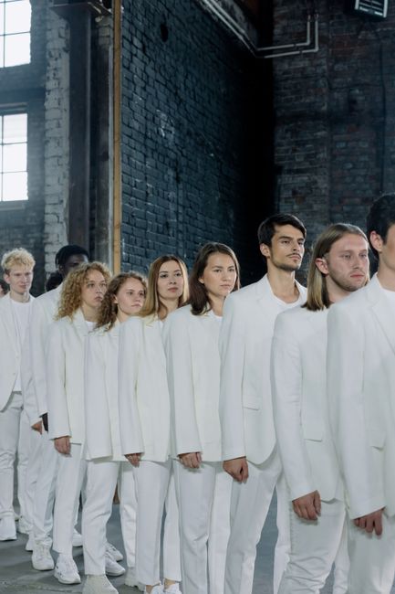 A diverse group of adults wearing white suits standing in a