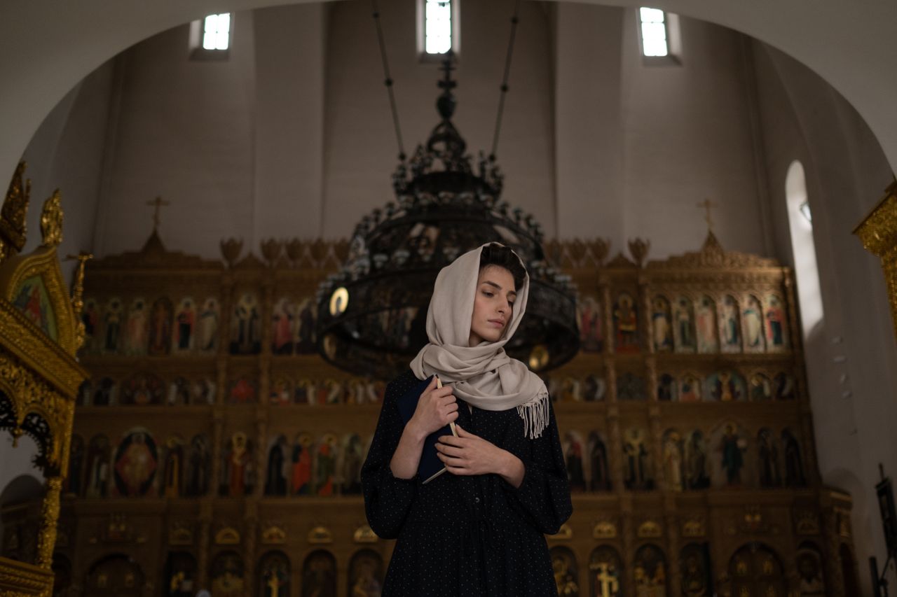 Woman in a dark modest dress and headscarf inside a church