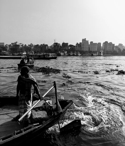 Free A fisherman navigates his boat across the river in Narayanganj, Bangladesh. Stock Photo