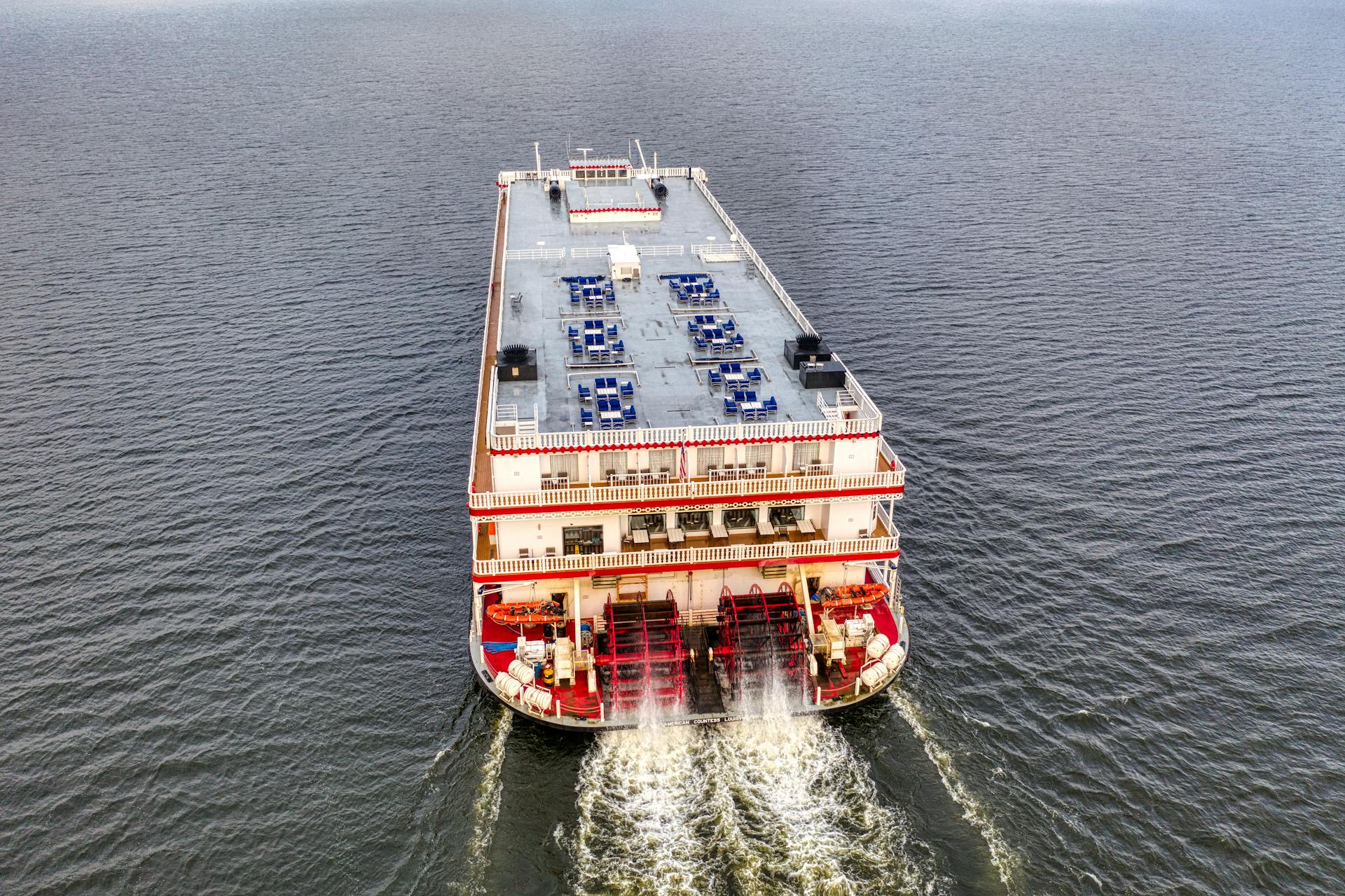 Aerial shot of a red and white historic paddle steamboat cruising on a vast river in Maple Springs, MN.