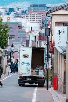 Delivery truck parked on a bustling urban street with buildings and people in the background.
