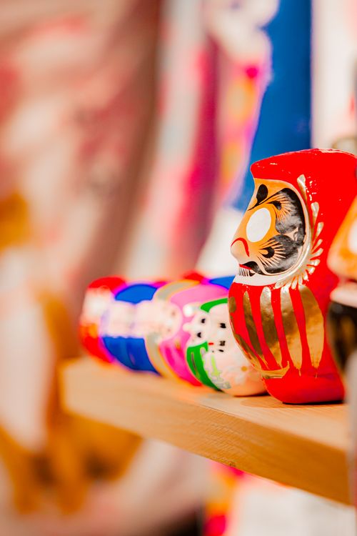 Free Vibrant Daruma dolls lined up on a wooden shelf in an artistic still life setting. Stock Photo