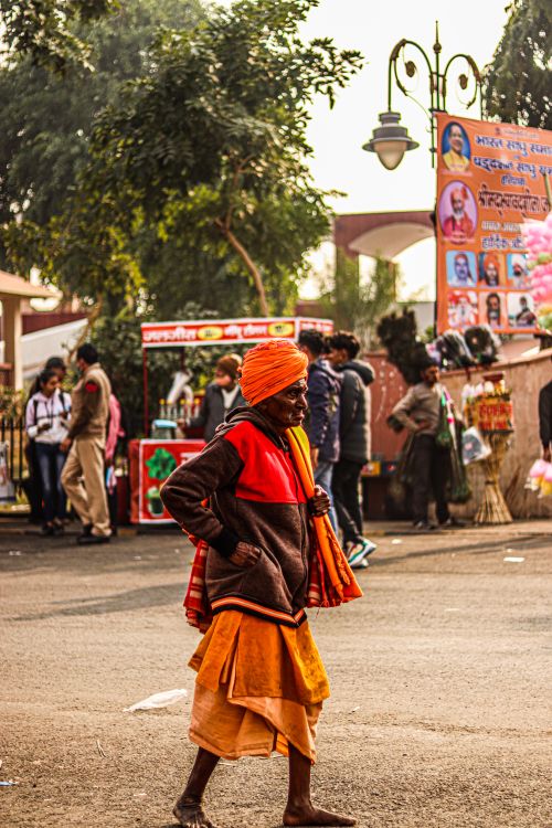 Free Elderly man in vibrant attire walking through a bustling street market outdoors. Stock Photo