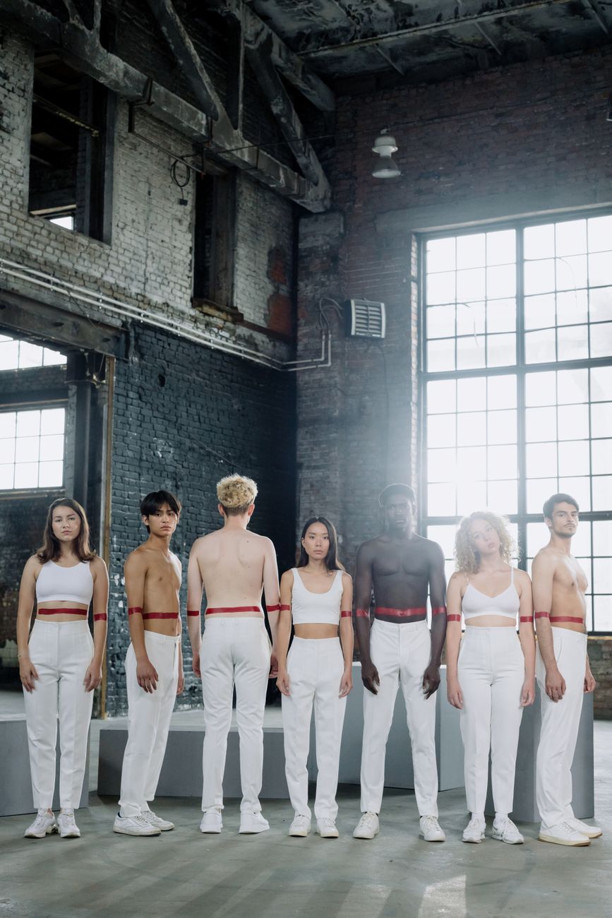 A diverse group of people in white outfits with red accents posed in an industrial setting.
