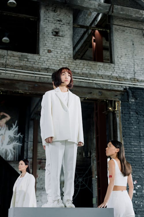 Woman in White Suit and Models Standing around