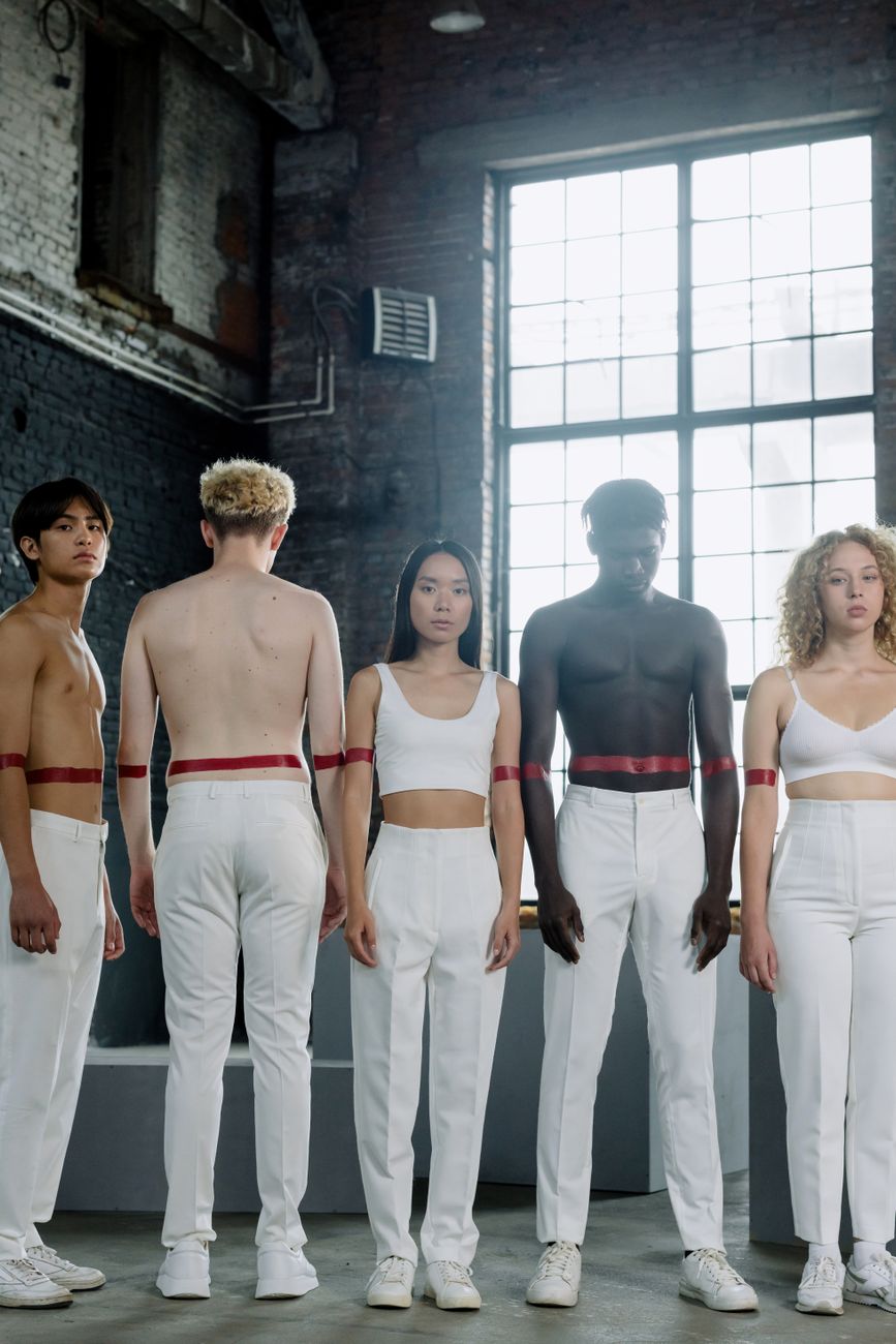 Diverse group of people in white attire with red accents standing indoors.