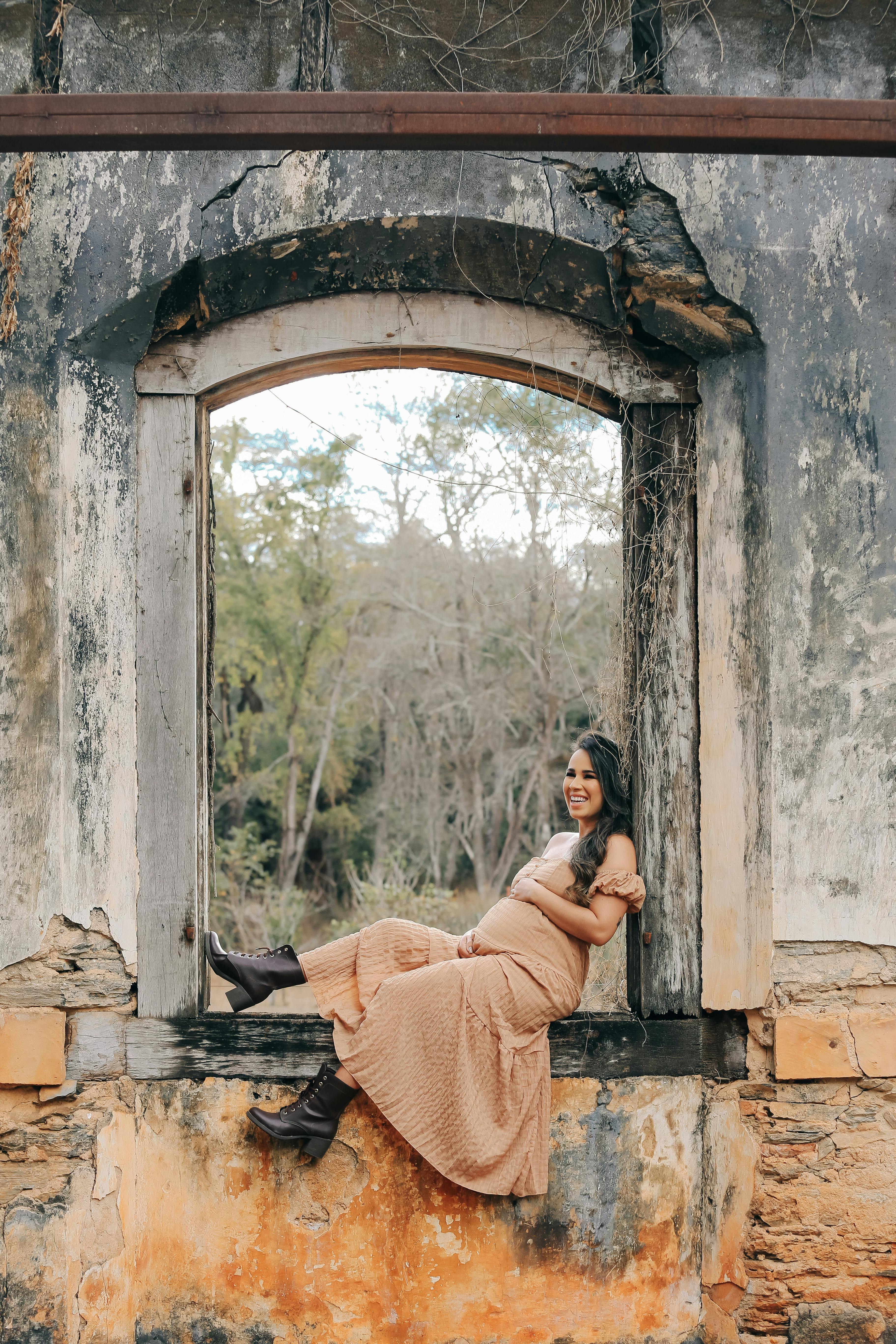 pregnant woman sitting in window of abandoned building