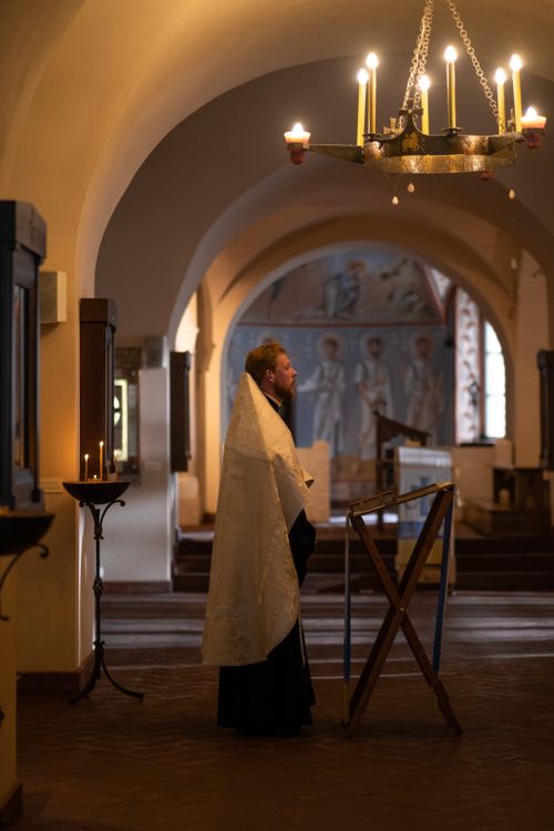 Free Orthodox priest standing in a dimly lit church interior, embodying faith and spirituality. Stock Photo
