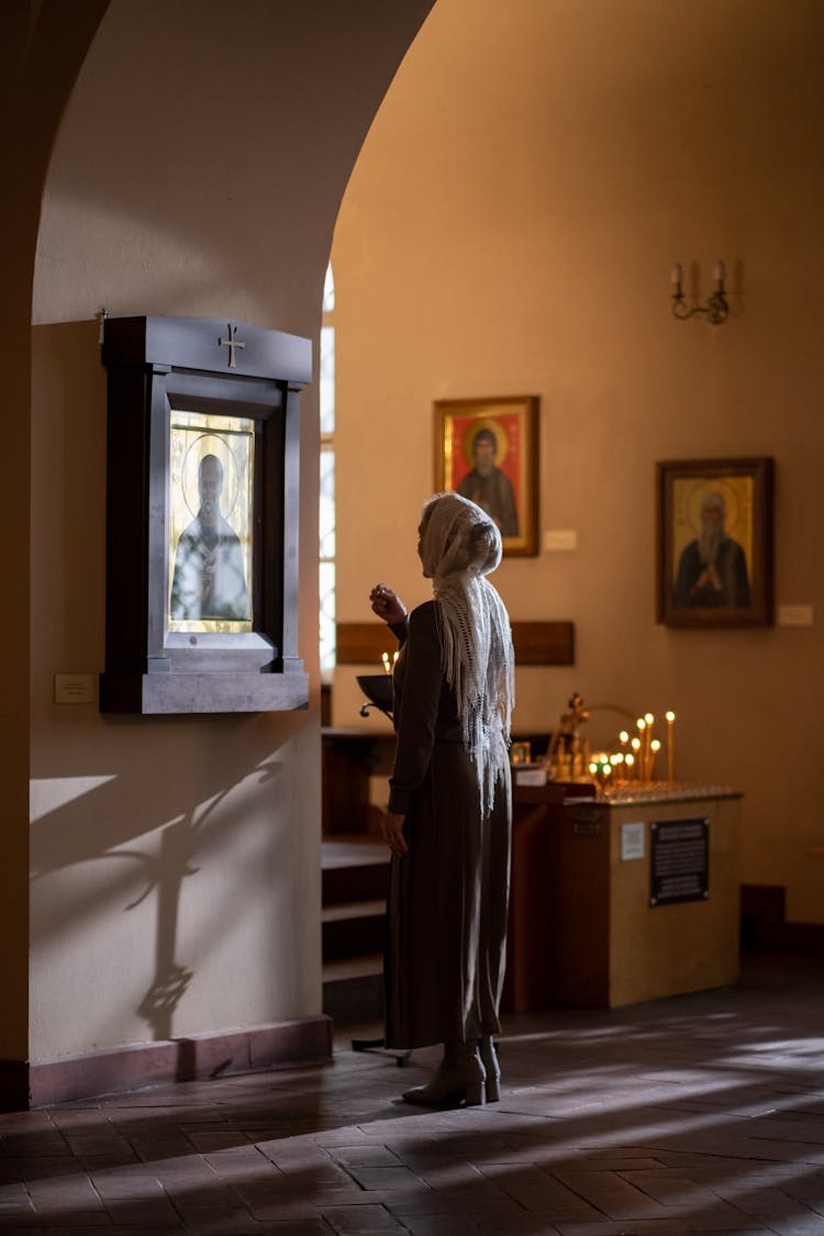 Woman Wearing Head Covering Praying Before Icon