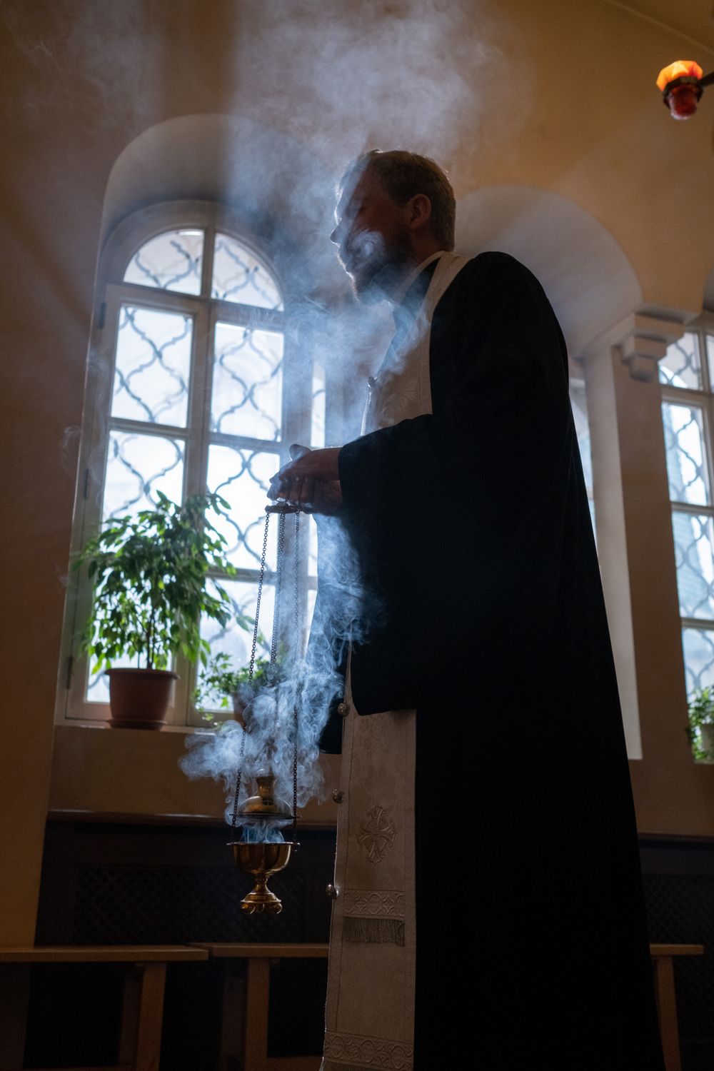 A priest holding incense in a church