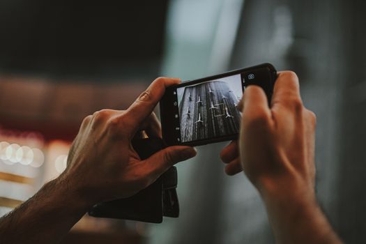 Hands holding a smartphone capturing an indoor scene in Dubai, featuring a modern lifestyle.