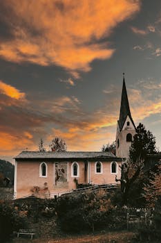 A quaint church against a dramatic golden sunset sky, nestled in a winter countryside.