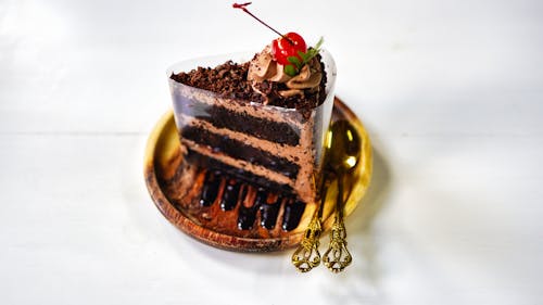 Free A Slice of Chocolate Cake with Cherry on Top on a Wooden Saucer Stock Photo