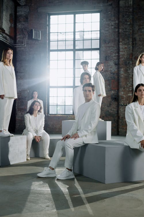 Women and Men in White Suits Standing and Sitting