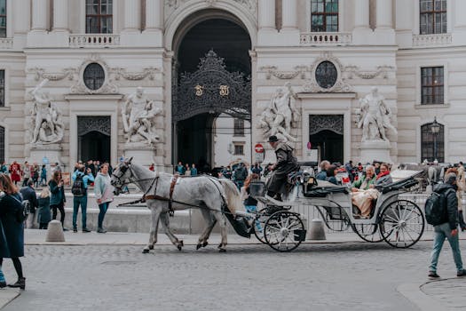Tourists enjoy a horse-drawn carriage ride at Hofburg Palace in Vienna, Austria, showcasing historic architecture.