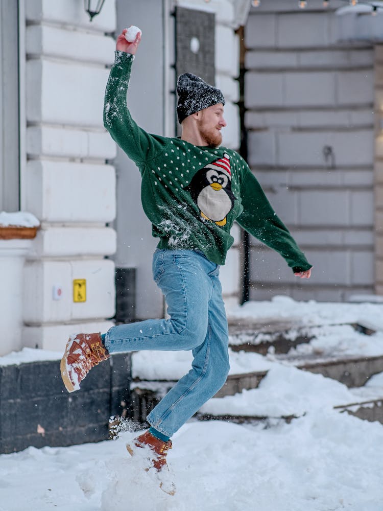 Man In Christmas Jumper Throwing Snowball