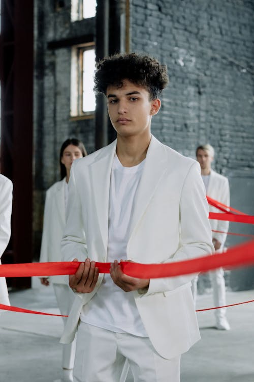 Man in White Suit Holding Red Ribbon