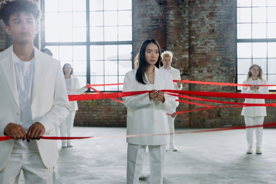 Models Standing in White Suits and Holding Red Ribbon