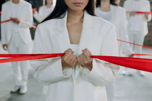 Woman in White Suit Holding Red Ribbon